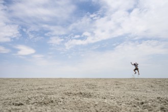 Symbolic picture, abstract, man jumping on the Etosha pan, salt pan, Etosha National Park, Namibia