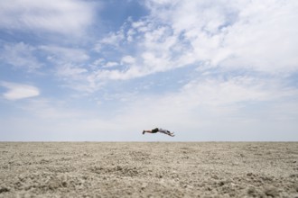 Abstract, man jumping horizontally at the Etosha pan, salt pan, Etosha National Park, Namibia