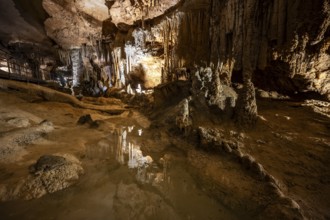 Stalactites and stalagmites, small underground lake, rock formations in a stalactite cave, Grotta