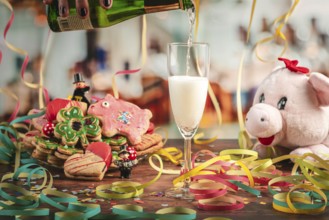 Pour sparkling wine into glass surrounded by New Year cookies, streamers and a plush pig