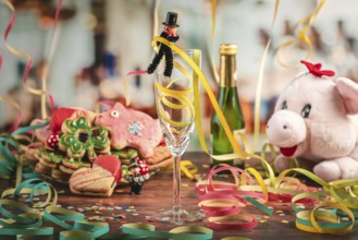Champagne glass surrounded by New Year cookies, streamers and plush pig