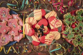 Various colorful cookies on wooden table with confetti, streamers and lucky charms