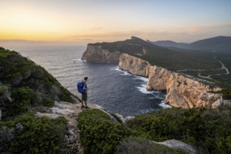 Tourist in front of coastal landscape at sunset, steep cliffs by the sea, cliffs in the evening