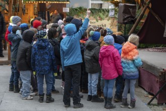 A group of children watches an acrobat on stage, Historischer Christmas market am Neustädter church