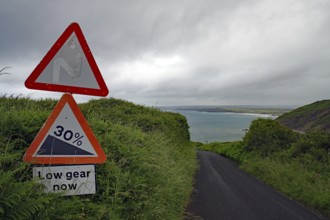A steep road sign stands out against a dramatic coastal landscape, Cornwall, United Kingdom