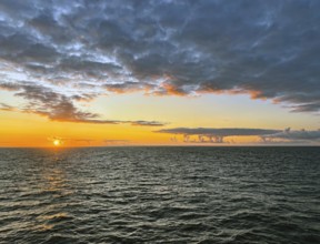 Tranquil ocean horizon at sunset with dramatic clouds and warm hues, Orkney Islands, Scotland,