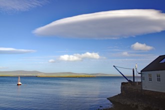 A tranquil ocean view with unique cloud formation and sailboat, UFO clouds, Stromness, Orkney