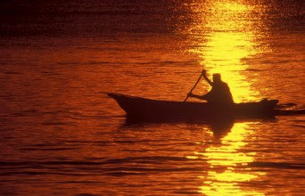 Silhouette of a fisherman in his boat at sunrise near Mikadi Beach, Dar es-Salaam, Tanzania,