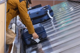 Tourist retrieving luggage from the baggage carousel in an airport terminal, celebrating the