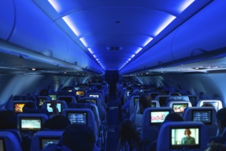 Passengers enjoying in flight entertainment while watching movies on personal screens, surrounded