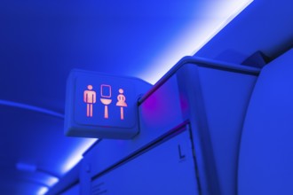 Illuminated restroom sign indicating availability with male and female symbols glowing red inside