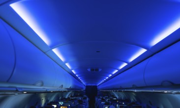 Blue cabin lights creating a relaxing atmosphere inside an airplane during a flight, with