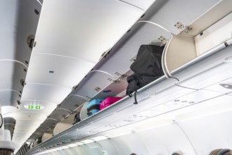 Carry on luggage and bags are neatly arranged inside the overhead compartments of an airplane