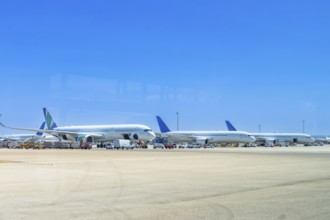 Several airplanes are parked on the tarmac at an airport, waiting for their next flights under a