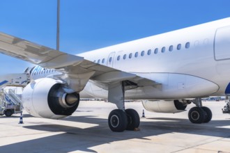 Passenger airplane parked on the airport runway, showcasing its wing, engine, and landing gear,