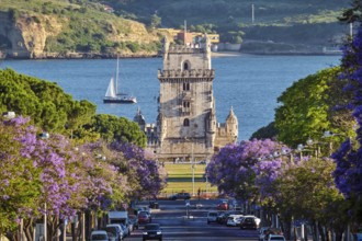Scenic view of Belem Tower in Lisbon, Portugal, seen over a street with blooming purple jacaranda