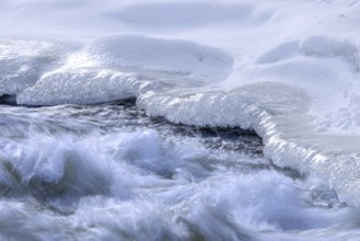 Ice formation formed by frost and freezing cold temperatures over running water of stream along