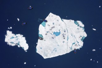 Aerial view over ecotourists from Iceland Pro Cruises walking on ice floe drifting in the Arctic
