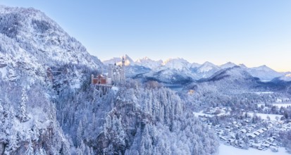 Neuschwanstein Castle is perched in the snowy alpine landscape, surrounded by peaceful forests