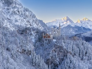 The magnificent Neuschwanstein Castle, surrounded by mountains and glowing snow in the morning