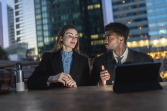 Business colleagues of different ethnicities are sitting at a table with a tablet, engaging in a