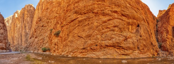 Panoramic view of gigantic red rock face under clear sky, Todra Gorge in Morocco