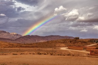 Colourful rainbow over a rural desert landscape with mountains in the background, Tinghir in