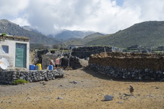 A simple stone building with mountains in the background, village at the foot of Great Ararat with