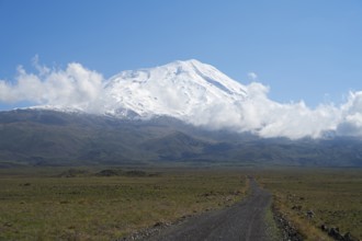A snow-covered mountain under blue sky with a path in the foreground, near Cevirme, Great Ararat,