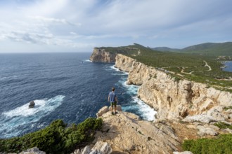 Tourist enjoying the view of steep cliffs by the sea, coastal landscape, cliffs on the Capo Caccia