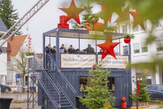 An elevated stage with musicians surrounded by Christmas decorations and spectators, Sindelfingen,