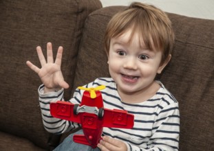 Little boy with gestures, 3 years old, playing with airplane indoors in Ystad, Skåne County,