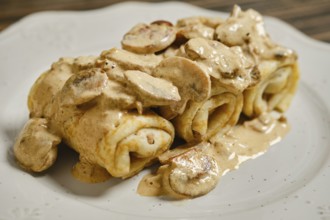 A tempting plate of stuffed crepes filled with savory meat and topped with a rich, creamy mushroom