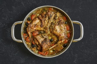 A delicious rabbit hind leg stew simmers in a large pot, featuring juicy meat surrounded by