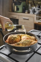 Close-up view of hand pouring dry white wine in a pot with rabbit hind legs and saddle