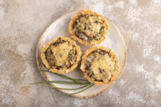 Tartlets with meat and cheese on brown concrete background. top view, flat lay, copy space