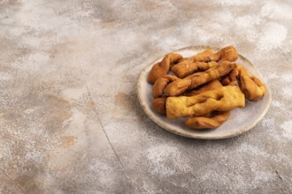 Crunchy biscuit Brushwood cookies sprinkled with powdered sugar on brown concrete background, side