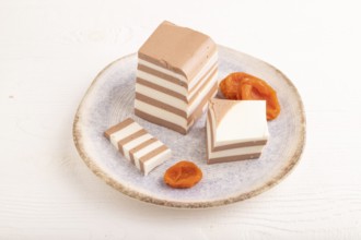 Cocoa and milk jelly with dried apricots on white wooden background, side view, close up,
