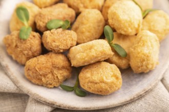 Fried crispy Chicken Nuggets with ketchup, microgreen on brown concrete background and linen
