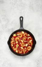 Greek saganaki, in an iron pan, saganaki with shrimp, shrimp in tomato sauce, with pepper and feta