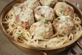 Spaghetti with chicken meatballs, with cream sauce, and parmesan cheese, and decorated with