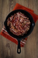 Crispy bacon, on a cast-iron skillet, on a wooden table, rustic style, no people