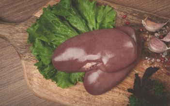 Raw pork kidneys, on a chopping board, close-up, top view, no people