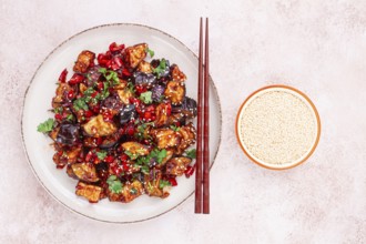 Fried eggplant, Chinese style, in sweet and sour sauce, with pepper and sesame seeds. on a white