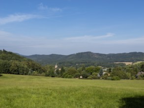 Small village with church in a gentle mountain landscape and meadows, Lusetian Mountains, Bohemia,