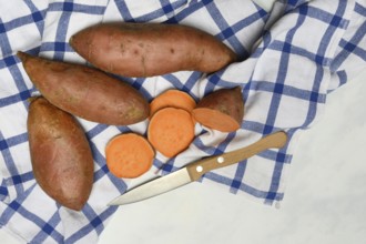 Sweet potatoes with kitchen knife on kitchen towel, Ipomoea batatas