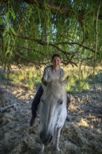 Young girl sitting on her horse under a tree, Othenstorf, Mecklenburg-Western Pomerania, Germany