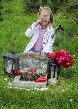 Grieving blonde 7-year-old girl at her cat's grave at pet cemetery in Ystad, Skåne County, Sweden,