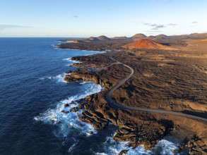 Coast with lava fields, volcanic landscape near Los Hervideros with red volcano Montaña Bermeja, in