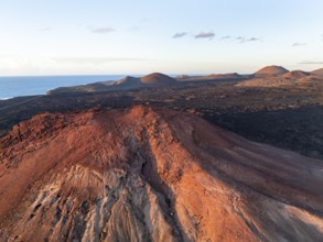 Picturesque volcanic landscape in evening light, red volcano Montaña Bermeja between lava fields,